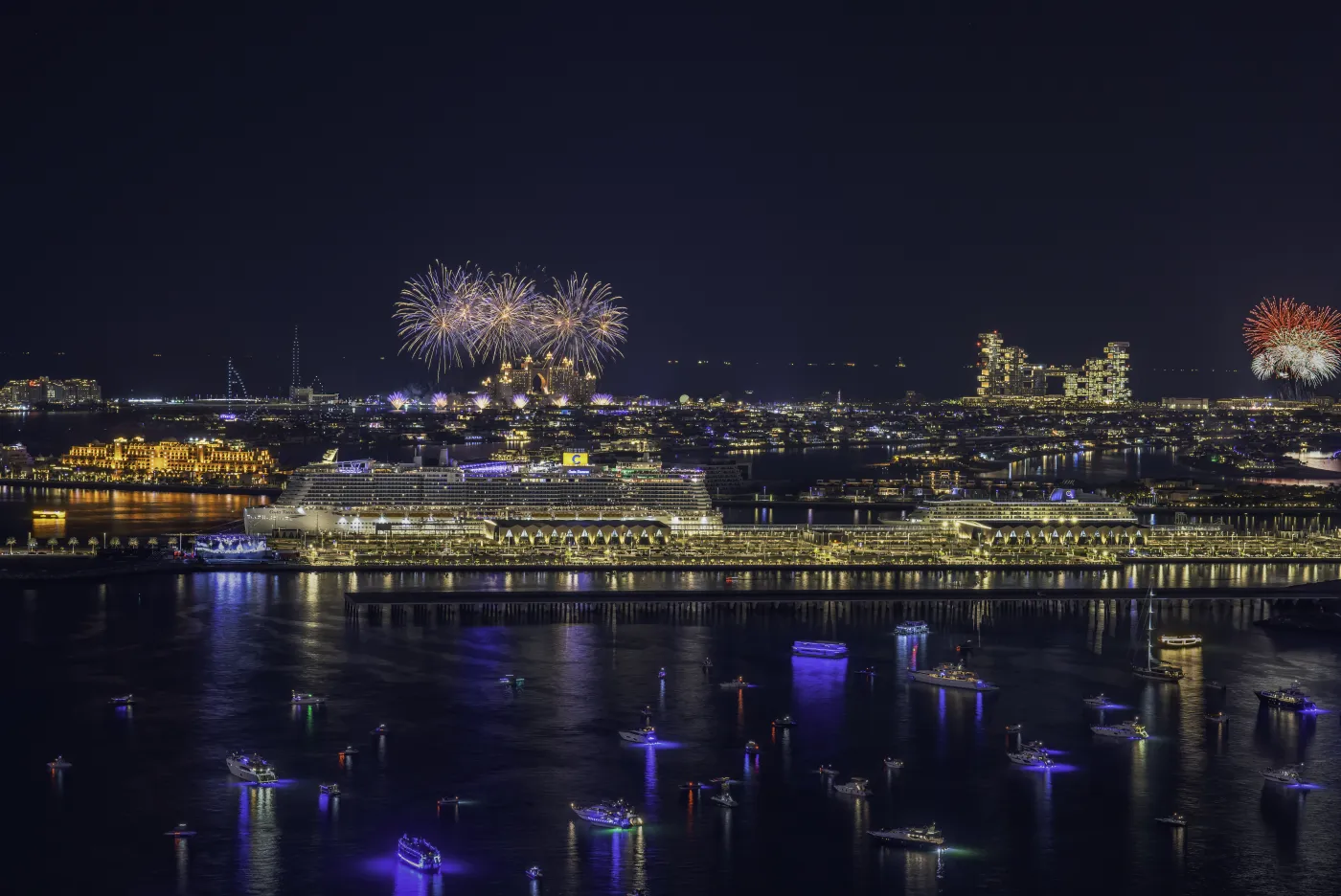 New Year's Eve fireworks bursting over Dubai Harbour and the city skyline, viewed from the water