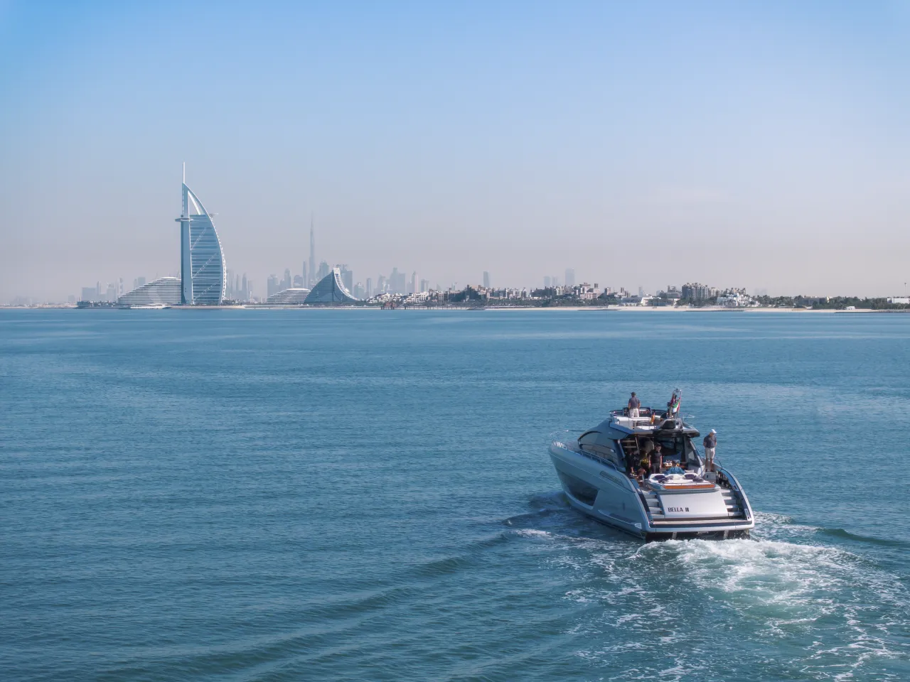 A crewed private charter yacht cruising past the Burj Al Arab and the Dubai skyline